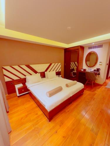 a bedroom with a large white bed and a mirror at Granada Hotel in An Najaf