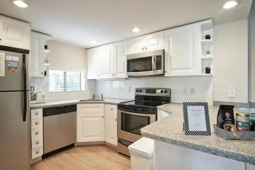 a kitchen with white cabinets and stainless steel appliances at Stroll to Siesta Beach from Serene Condo + (bikes) in Siesta Key