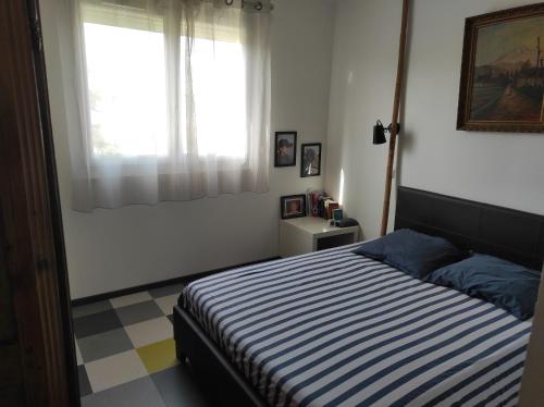 a bedroom with a striped bed and a window at T3 PRADO St-GINIEZ in Marseille