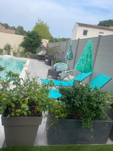 a patio with two blue chairs and a pool at L'Hacienda, Haut de villa de deux chambres, avec salle de bain et toilettes WC privative in Fréjus