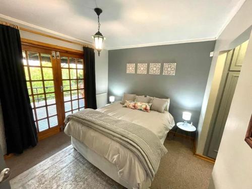 a bedroom with a bed in a room with windows at The Hedge at Dullstroom Cottage in Dullstroom
