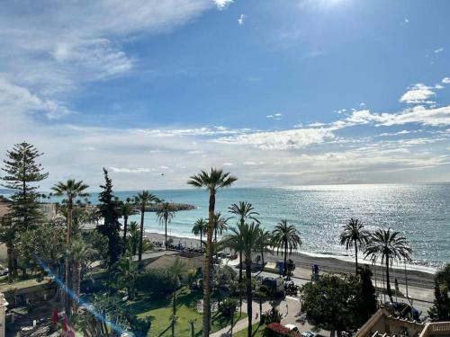 une vue sur une plage avec des palmiers et l'océan dans l'établissement The view-Centre- Clim -Parking-vue mer-plage, à Menton