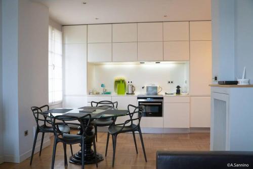 une cuisine avec une table et des chaises dans une pièce dans l'établissement Moderne 2 pièces en plein Paris au bord de Seine, à Paris