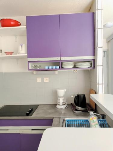 a kitchen with purple cabinets and purple counters at TROP COOL in Cap d'Agde