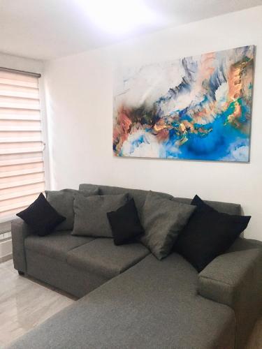 a couch in a living room with a painting on the wall at Casa a 12 minutos de CIVAC Cuernavaca. in Atlacomulco