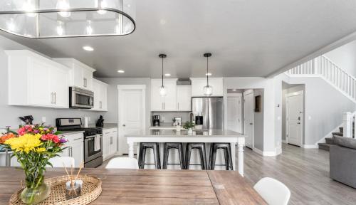 a kitchen with white cabinets and a wooden table at 8 Beds 2 Full Kitchens Fenced HUGE Yard & Parks! in Saratoga Springs