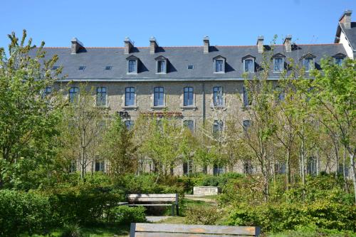 a large building with a lot of trees and benches at Brit Hotel Spa Le Connetable in Dinan