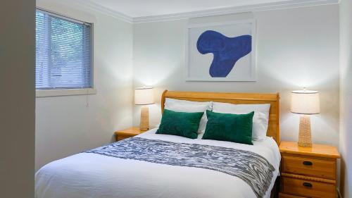 ein Schlafzimmer mit einem Bett mit grünen Kissen und zwei Lampen in der Unterkunft The Stonewater in Madeira Park