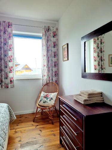 a bedroom with a dresser and a chair and a window at Villa Dorota in Zakopane