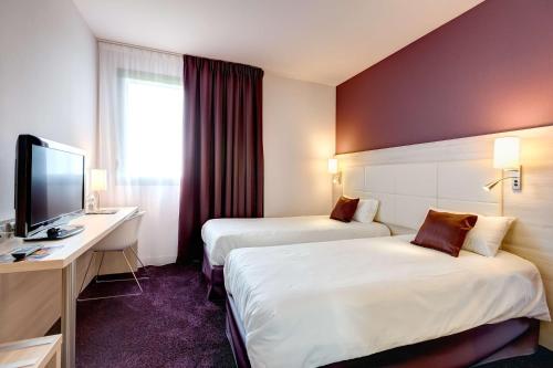Habitación de hotel con 2 camas, escritorio y TV. en Brit Hotel Vendée Mer, en La Mothe-Achard