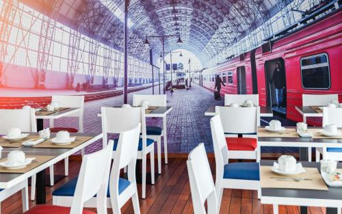 a restaurant with tables and a train station at Brit Hotel de Paris Saint-Jean-de-Luz in Saint-Jean-de-Luz
