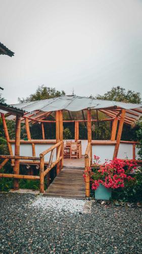 a wooden boardwalk with a large umbrella and flowers at Eco Hotel Terrabella in Santa Elena