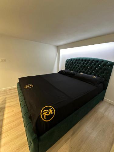 a bedroom with a black bed with a gold logo at Rent Room 2 Rolandi Apartments in Pogradec