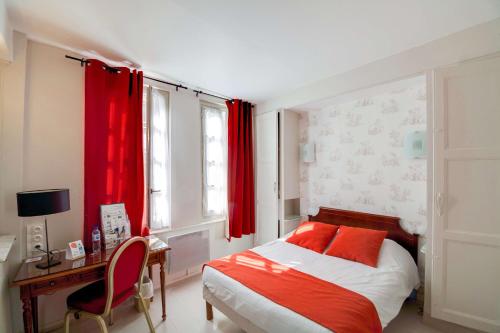 a bedroom with a bed and a desk and red curtains at Brit Hotel Comtes De Champagne - Troyes Centre Historique in Troyes