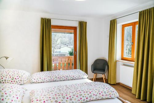 1 dormitorio con cama, ventana y silla en Ferienwohnungen Quellenhof, en Bad Reichenhall