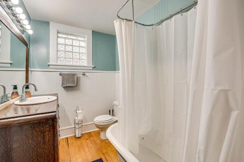 Un baño con una cortina de ducha blanca y un inodoro. en Charming Decatur Oakhurst Bungalow with Patio!, en Decatur