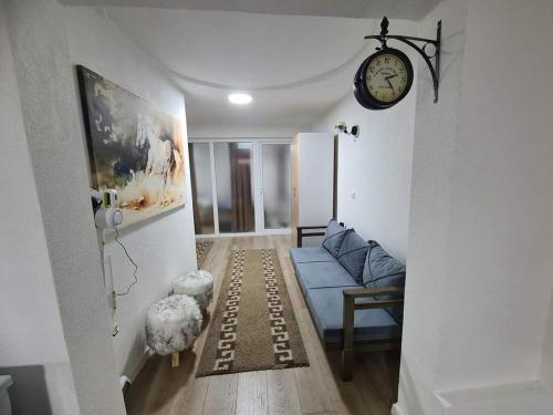 sala de estar con sofá azul y reloj en Apartments Gjakove, en Gjakove