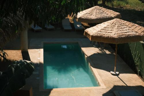 a swimming pool with an umbrella and some chairs at Casa Akaw in Temalhuacán