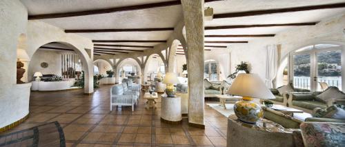 a living room with couches and chairs in a building at Club Hotel Baja Sardinia in Baja Sardinia