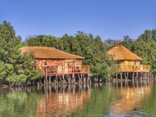 two wooden huts on a bridge over a body of water at Bintang Bolong Lodge in Bintang