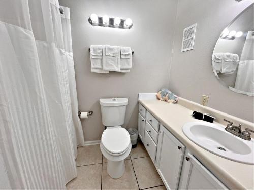 een badkamer met een toilet, een wastafel en een spiegel bij Sea Breeze 318 in Gulf Shores