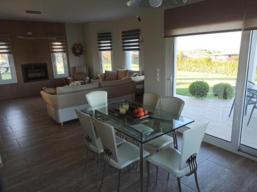 a dining room with a glass table and white chairs at Zeusplace Olympous Riviera Villa 1 in Litochoro
