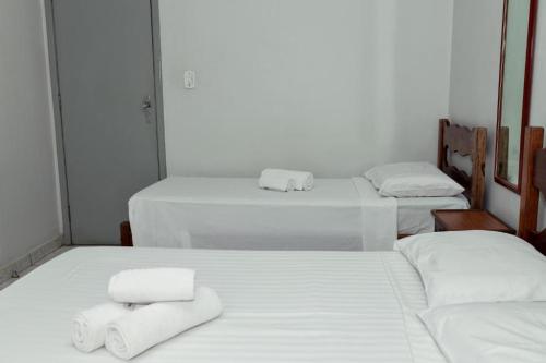 three beds in a room with white sheets and towels at Carlton Express Imbiara in Araxá