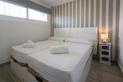 Un dormitorio blanco con dos camas y una ventana. en Balcón Tridente, en Alicante
