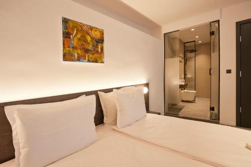a bed with white pillows and a painting on the wall at Bizarre Boutique Hotel in Varna City