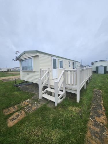 a mobile home with a porch on the grass at Kingfisher OAK 1098 Dees Caravan Lettings in Ingoldmells