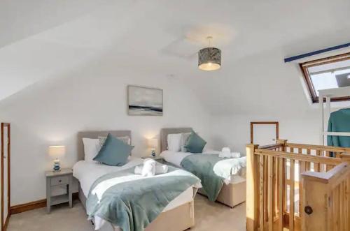 a bedroom with two beds and a staircase at Turnstones - Seaside Home - Free Street Parking in Sheringham