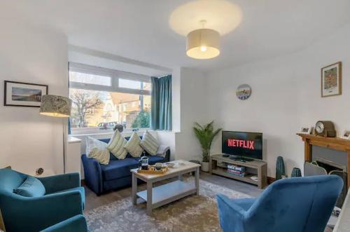 a living room with blue chairs and a tv at Turnstones - Seaside Home - Free Street Parking in Sheringham