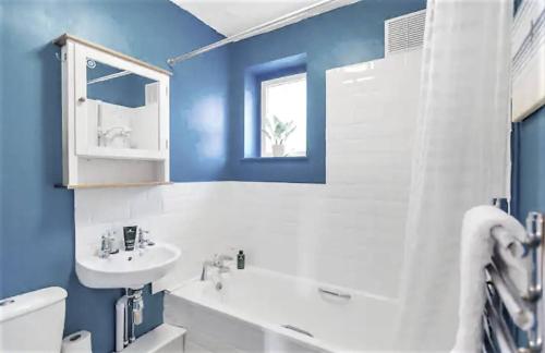 a blue bathroom with a sink and a toilet at Cosy and Fresh Seaside Home - Parking in Sheringham