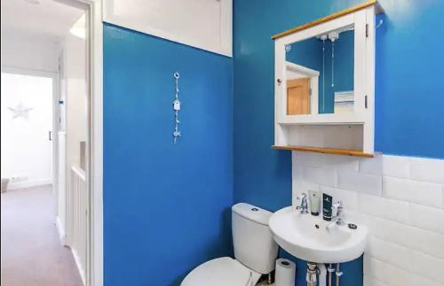 a blue bathroom with a toilet and a sink at Turnstone Retreat - Parking in Sheringham