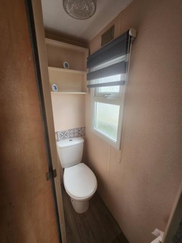 a small bathroom with a toilet and a window at Kingfisher OAK 1098 Dees Caravan Lettings in Ingoldmells