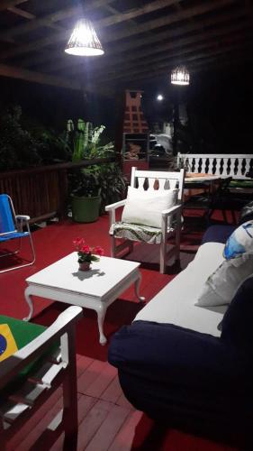 a living room with two white chairs and a table at Sobrado parte de cima vista para mar in Ilhabela
