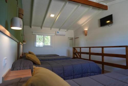 1 dormitorio con 2 camas y TV en la pared en Motel A.C.A. Cipolletti en Cipolletti