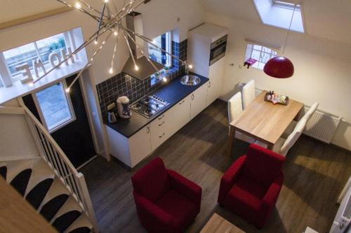 a kitchen and dining room with a table and red chairs at Appartement Pieterom in Sleen