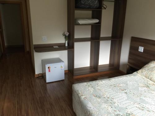 a bedroom with a bed and a small refrigerator at Hotel Vila Nova in Teresópolis