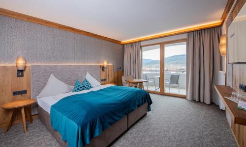 a hotel room with a bed and a large window at Hotel Königgut in Wals