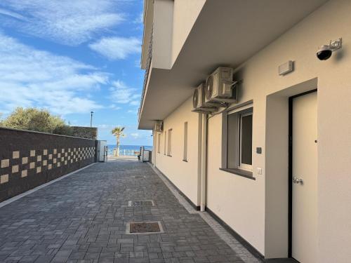 une passerelle entre deux bâtiments avec l'océan en arrière-plan dans l'établissement Thetis Apartments, à Furci Siculo