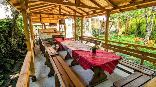 a row of wooden tables on a porch with a red table cloth at Pamir Guest House in Shipkovo