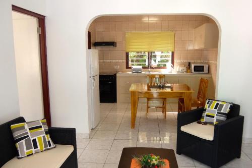 a kitchen and living room with a table and chairs at Roche Kerlan Apartments in Anse Possession