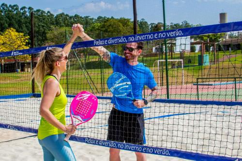 a man and a woman holding rackets on a tennis court at Blue Tree Thermas de Lins Resort in Lins