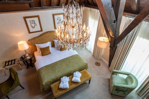 a bedroom with a large bed and a chandelier at Grand Hotel Casselbergh in Bruges