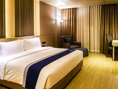 a hotel room with a large bed and a chair at Zayn Hotel Bangkok - Airport Link Access in Bangkok