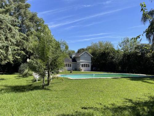 a large house with a swimming pool in a field at Casa Leloir in Villa Leloir