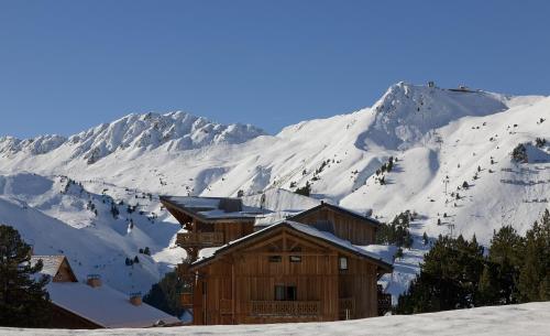 a ski lodge in the snow next to a mountain at Hôtel Club mmv Altitude **** in Arc 2000