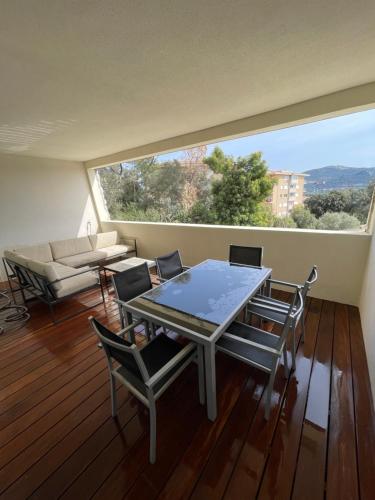 une table et des chaises dans une pièce avec une grande fenêtre dans l'établissement Grand Studio moderne tout confort, à Porto-Vecchio