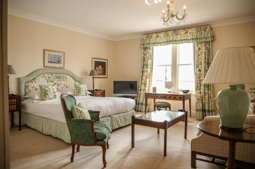 a bedroom with a bed and a chair and a table at Kinloch House Hotel in Blairgowrie